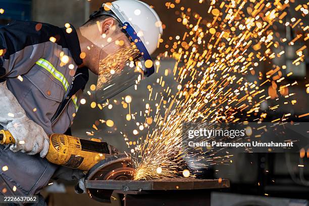 close-up view of a grinding operation in progress. sparks fly as the circular saw slices through metal, highlighting expert technique, heat, and energy in a professional, safety-conscious factory setting. - grinding stock pictures, royalty-free photos & images
