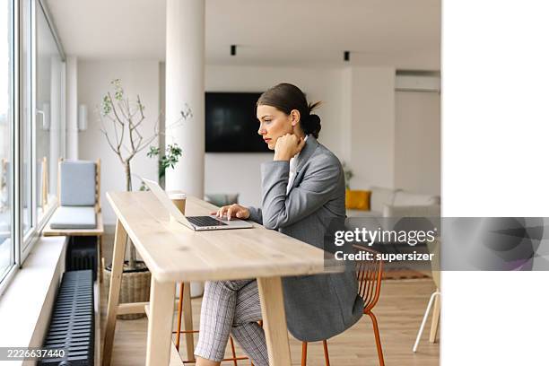 mujer profesional trabajando en una computadora portátil en un escritorio - una sola mujer joven fotografías e imágenes de stock