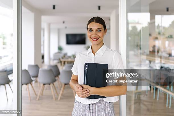 smiling woman in business attire holding a tablet - alleen één jonge vrouw stockfoto's en -beelden