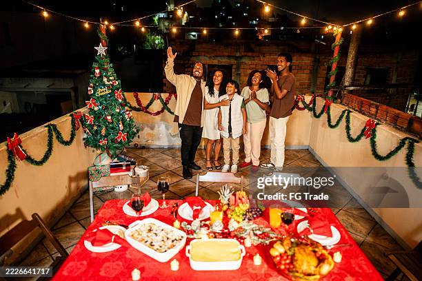 family embracing and looking for fireworks during christmas night on house rooftop - teenager outside apartment building stock pictures, royalty-free photos & images