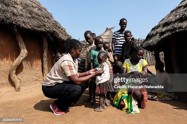 Health worker measuring a child's mid-upper-arm circumference during a family-led nutrition screening at Kalojuka village in Kotido district on July...