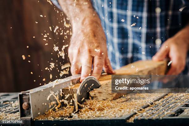 männliche zimmermann mit elektrischen kreissäge in heimat-werkstatt mit holzspäne fliegen - kreissäge stock-fotos und bilder