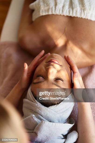 woman is lying down during a facial massage. - facial massage stock pictures, royalty-free photos & images