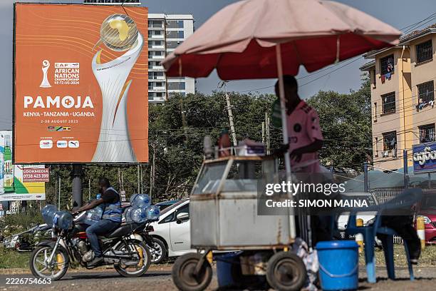 Street vendor sells food next to a billboard advertising the CAF African Nations Championship 2024 finals in Nairobi on July 28, 2025.