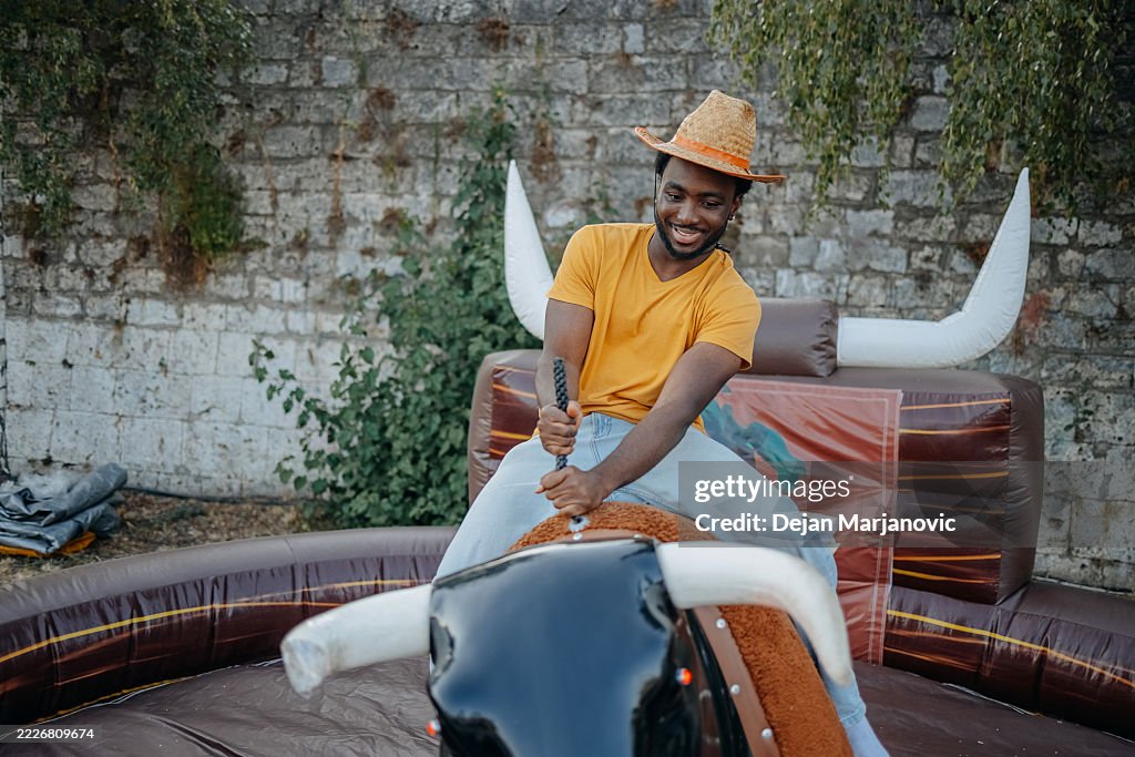 People having fun in the city riding mechanical bull outdoors