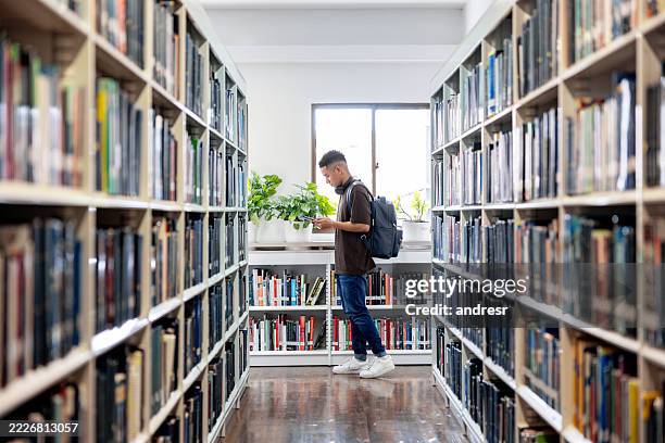 college student walking around the aisles of a library - public library stock pictures, royalty-free photos & images