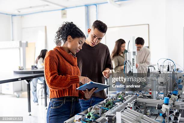 robotic students using a digital tablet while operating a production line robot - vetenskaplig forskning bildbanksfoton och bilder
