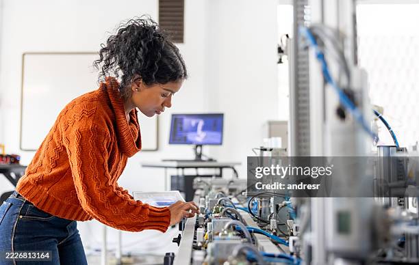 engineering student using a tablet while operating a production line robot - stereotypical stock pictures, royalty-free photos & images