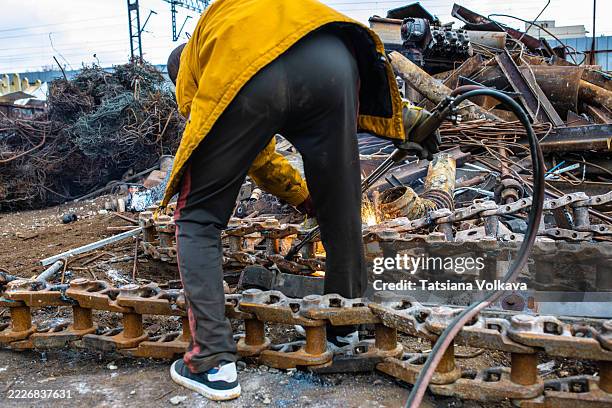 worker wearing protective gear welding heavy metal chains in a scrap yard - automatic welding torch stock pictures, royalty-free photos & images