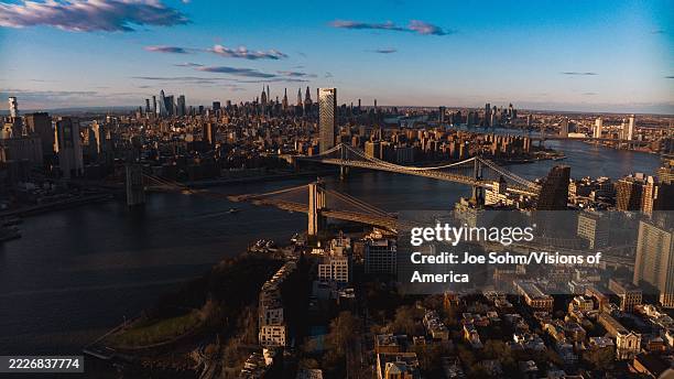 Sunset dusk on NYC Skyline from Brooklyn view over East River and Manhattan features on Brooklyn Bridge.