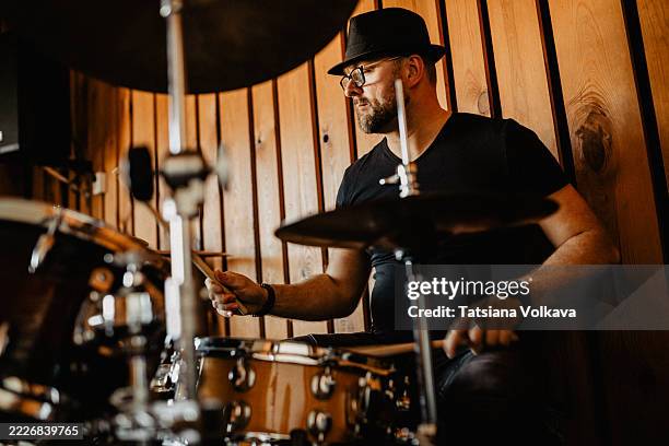 musician playing drums in a studio setting with a wooden background - drum stockfoto's en -beelden