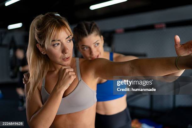 two women training boxing punches in a gym - self defence stock pictures, royalty-free photos & images