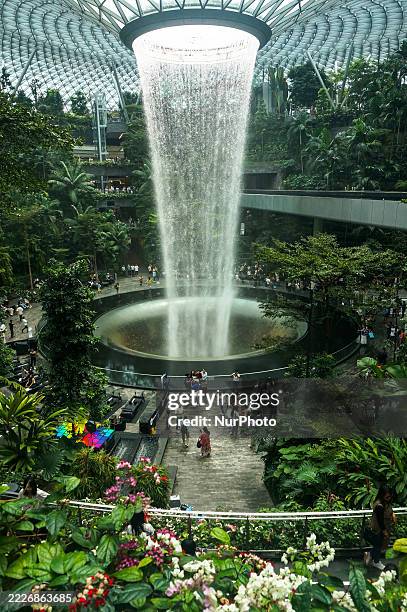 People visit the Rain Vortex indoor waterfall feature at Jewel Changi Airport mall in Singapore on July 11, 2025.