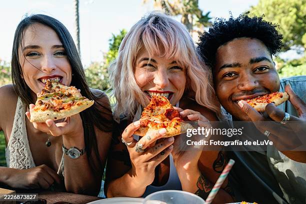 three young friends enjoying pizza outdoors in summer - southern european descent stock pictures, royalty-free photos & images
