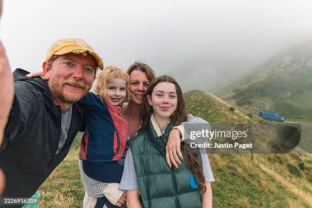 a family take a selfie in the pyrenees mountains. the views are obscured by low level cloud/fog/mist. but they are still having a good time! - famiglia con due figli foto e immagini stock