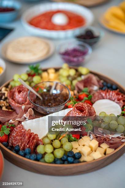 colorful charcuterie board with fresh fruits and cheeses on a kitchen counter - charcuterie stock pictures, royalty-free photos & images