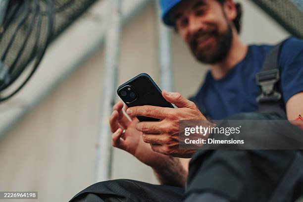 construction worker using smartphone on site during break - trabalhador manual imagens e fotografias de stock