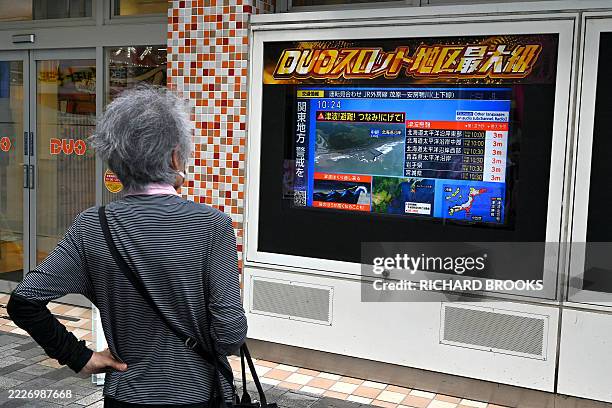 Woman watches a television broadcast of a tsunami warning for much of coastal Japan following a 8.7 magnitude quake in the sea off eastern Russia,...