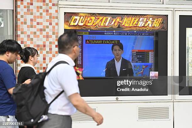 People Walk along a screen broadcasting televised information on an alert tsunami in Japan on July 30 in Tokyo, Japan. Following the magnitude 8.7...