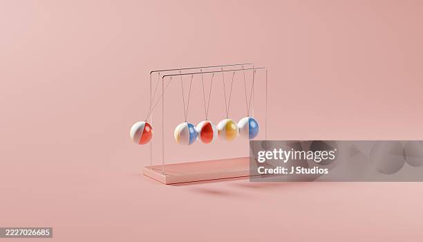 dynamic newton’s cradle with colorful beach balls reflecting summer fun and vacation spirit - movimiento perpetuo fotografías e imágenes de stock