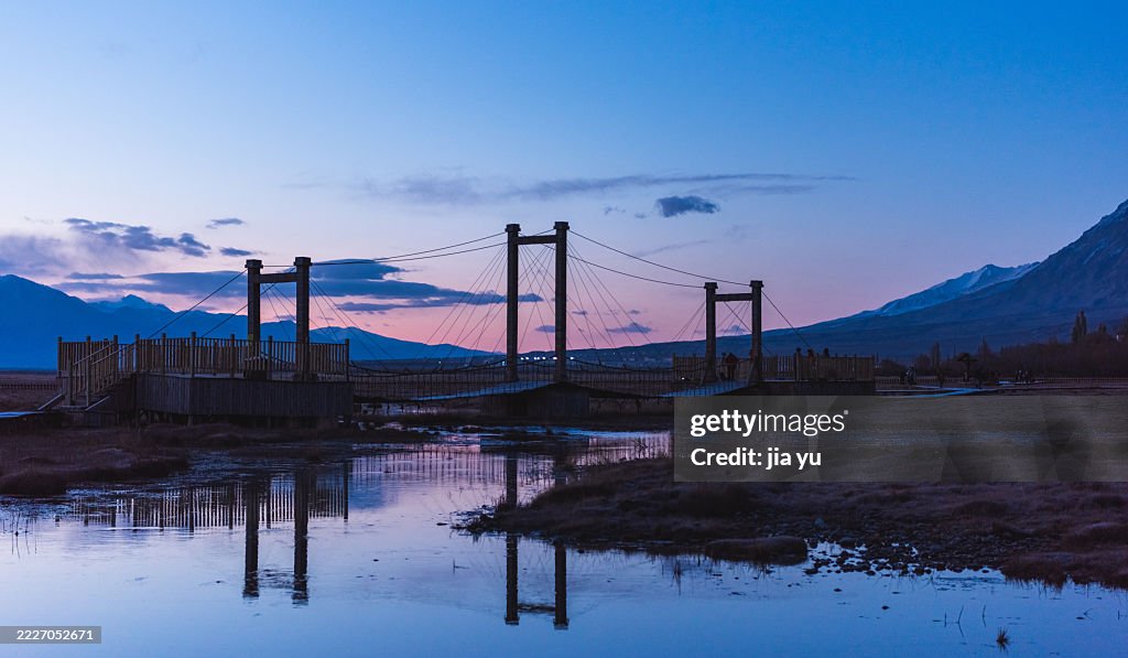 Serene Suspension Bridge Over Calm Water at Dusk