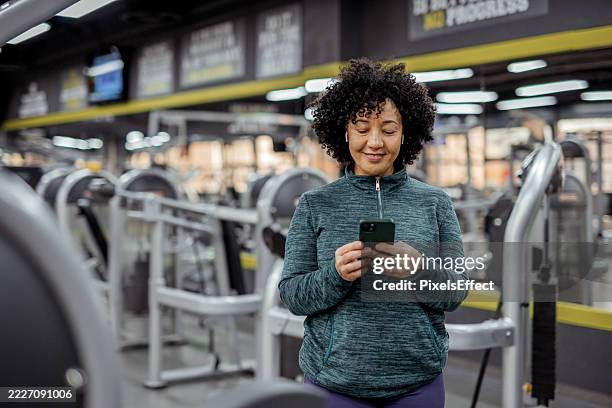 mature plus-size woman energized by music during gym session - in ear headphones stock pictures, royalty-free photos & images