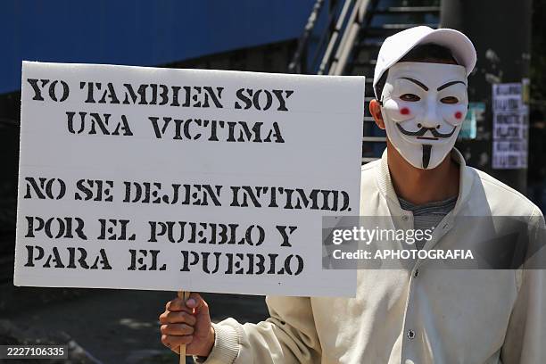 Student wears a Guy Fawkes mask as he carries a sign that reads " I was a victim too. Don't be intimidated. For the people and by the people", during...