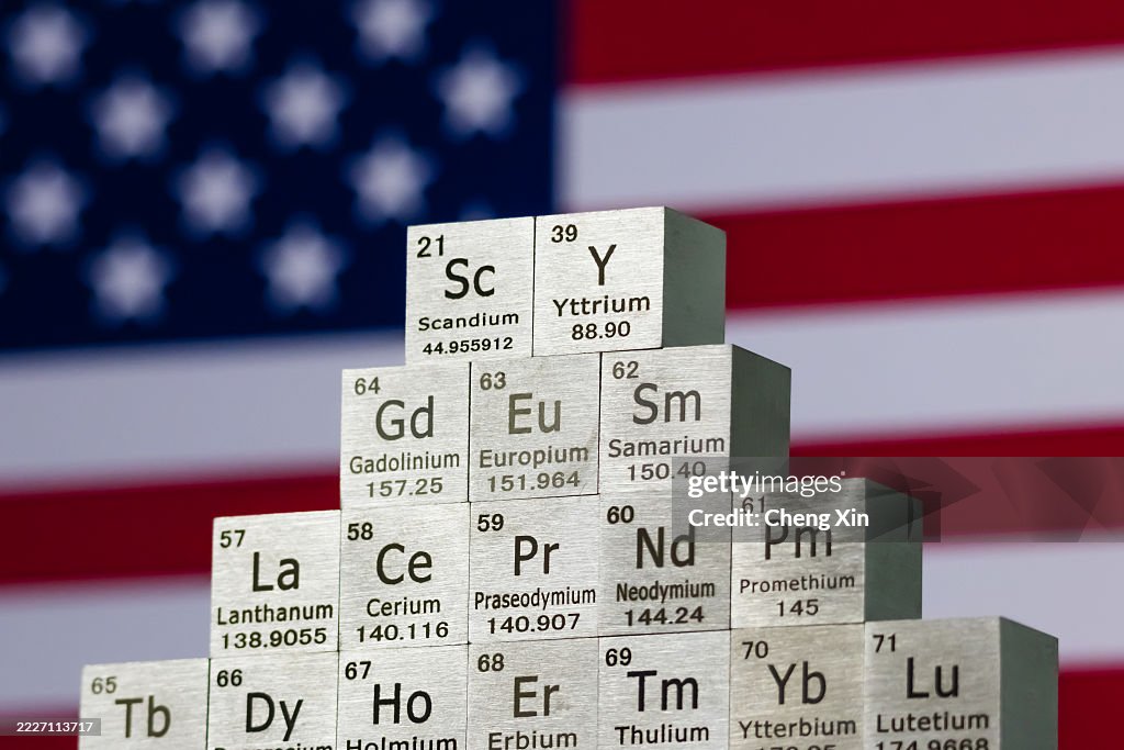 Rare earth element cubes stacked in front of United States flag