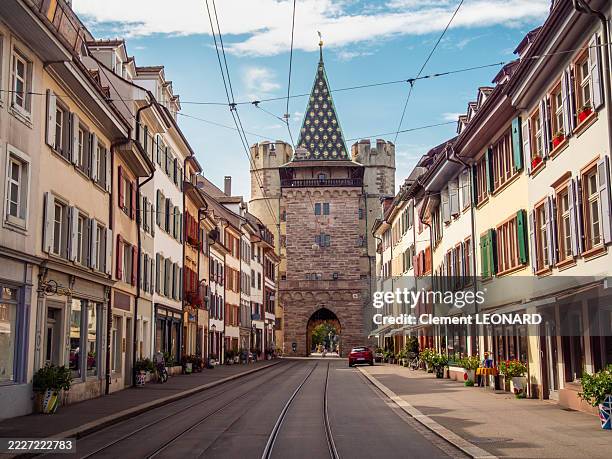 view of a street with multicolour buildings, tramway tracks and a perspective on the spalentor (gate of spalen or gate of saint paul), a classified historic monument and medieval city gate, basel - basel-stadt, switzerland. - basel switzerland stock pictures, royalty-free photos & images