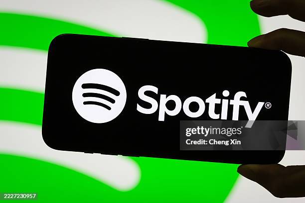In this photo illustration, a person holds a smartphone displaying the logo of Spotify Technology S.A. , a leading global audio streaming...