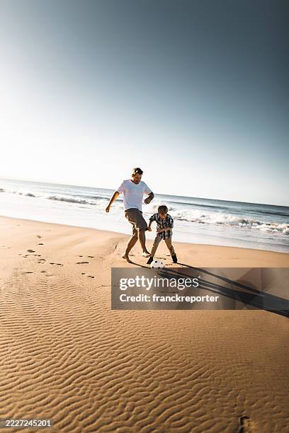 dad and son playing soccer on the beach - grandpa son stock pictures, royalty-free photos & images