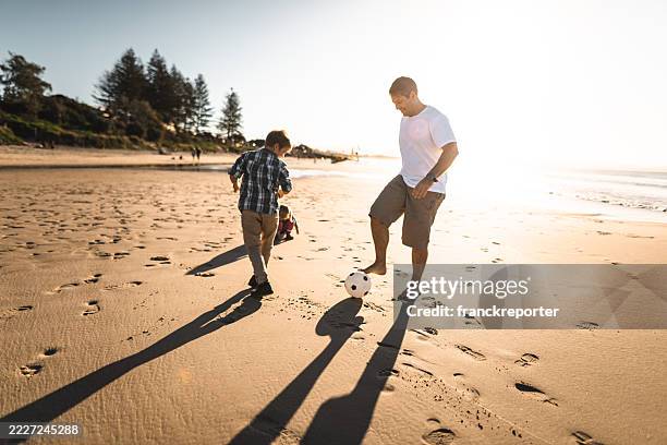 dad and son playing soccer on the beach - grandpa son stock pictures, royalty-free photos & images