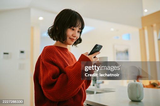 Woman reads an article on her smartphone while relaxing at home Woman reads an article on her smartphone while relaxing at home