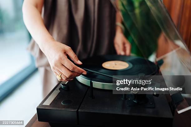 cropped hand of asian senior woman playing music on turntable in the living room at home. relaxing lifestyle, people and retirement. - soundtrack stock pictures, royalty-free photos & images