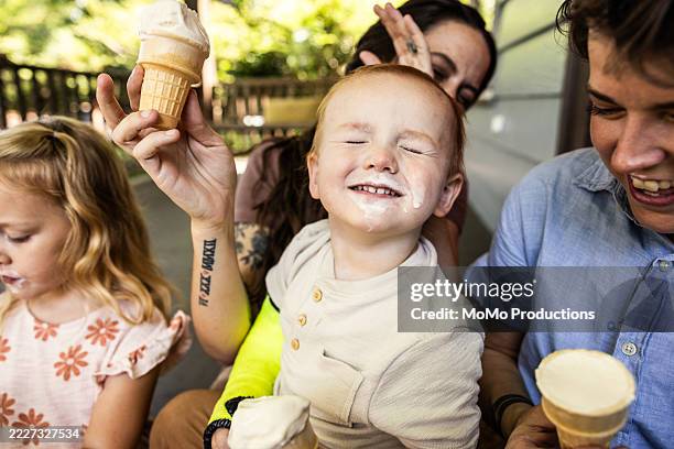 young family eating ice cream on front porch - girl eating messy ice cream cone stock pictures, royalty-free photos & images