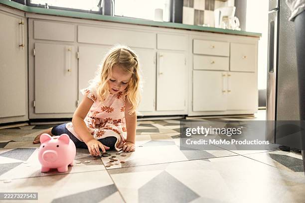 young girl putting change in piggybank in kitchen - counting stock pictures, royalty-free photos & images