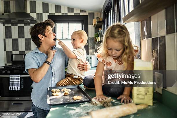 lesbian couple in kitchen making cookies with children - baking sheet stock pictures, royalty-free photos & images