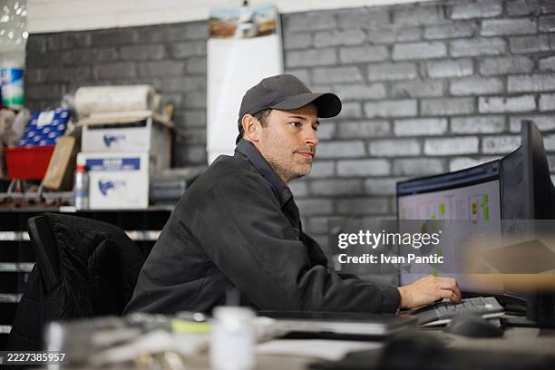 mecánico de automóviles trabajando en una computadora en un garaje - típico de la clase trabajadora fotografías e imágenes de stock