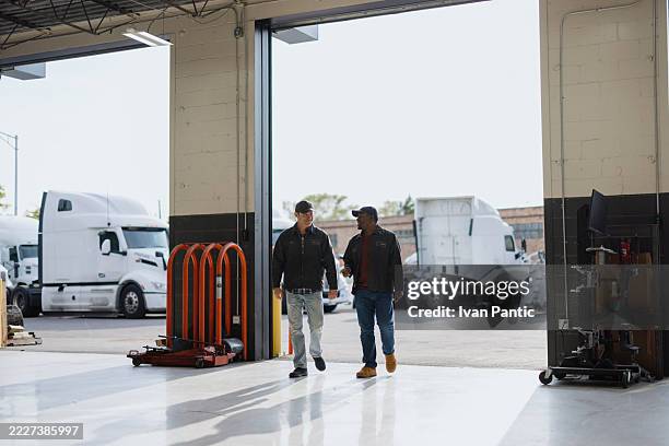 truck mechanics walking and talking in a repair garage - haulage stock pictures, royalty-free photos & images