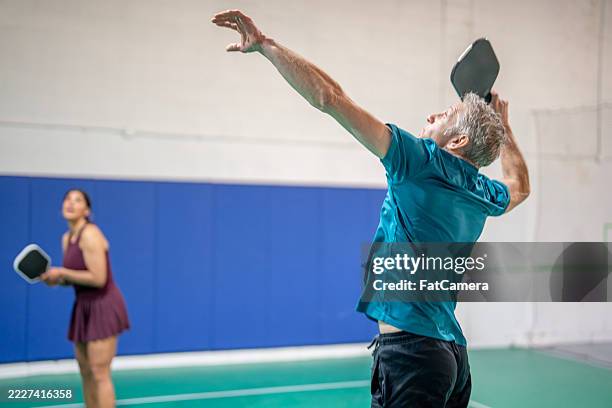 two focused players competing in exciting indoor pickleball match - paddle ball stock pictures, royalty-free photos & images