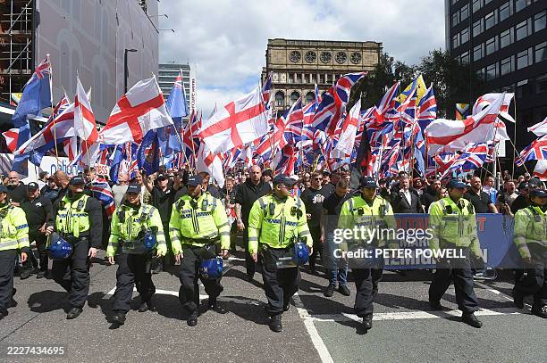 Police walk ahead of far-right Britain First party supporters waving Union Flags and St George Cross flags during an anti-immigration 'March for...