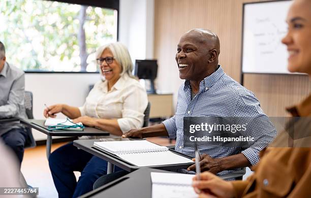 mature man going back to school and laughing in class while having a debate - classroom training stock pictures, royalty-free photos & images
