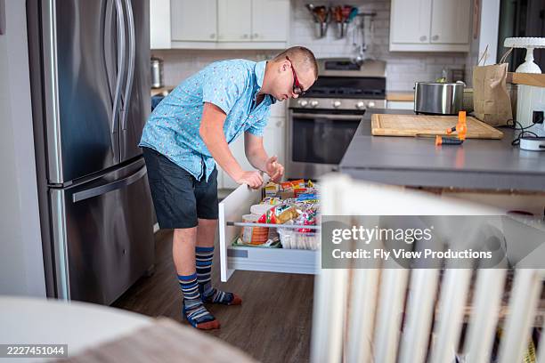 teenager looking for snack in kitchen - voorraadkast stockfoto's en -beelden