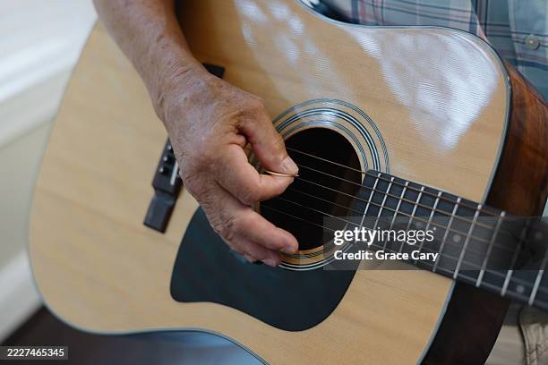 senior man plays acoustic guitar at home - chitarra acustica foto e immagini stock