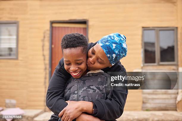 mother embracing and kissing her son - south african culture stock pictures, royalty-free photos & images