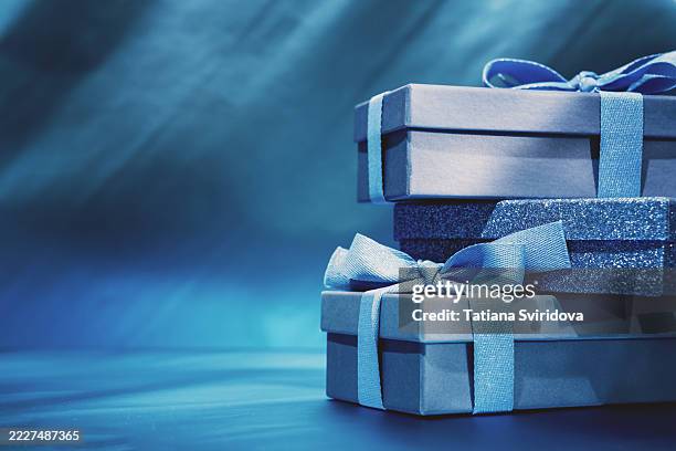 blue gift boxes stacked with bow ribbon on dark blue gradient background - blue present stock pictures, royalty-free photos & images