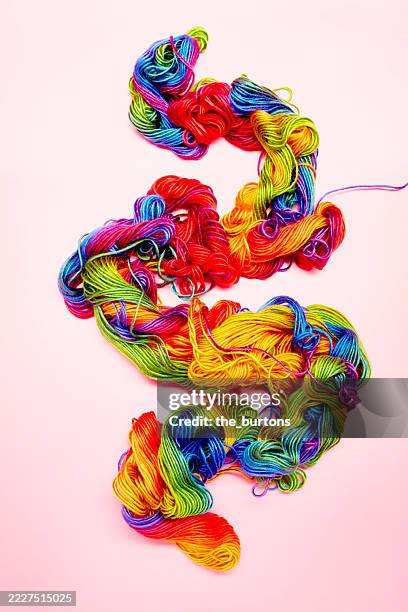 high angle view of colorful wool in shape of a human intestine on pink background - darmen stockfoto's en -beelden