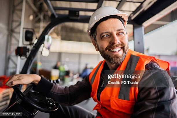 employee working on a forklift in a warehouse - forklift driver stock pictures, royalty-free photos & images