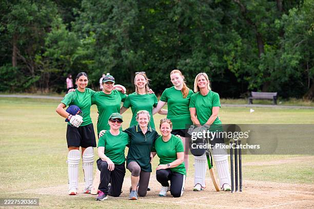 formal portrait of mixed age range female cricket team on a grass pitch in summer - cricket team stock pictures, royalty-free photos & images