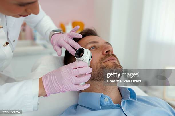 professional skin screening by dermatologist using modern device - dermatologist stock pictures, royalty-free photos & images